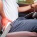 Man holding his back in pain while driving