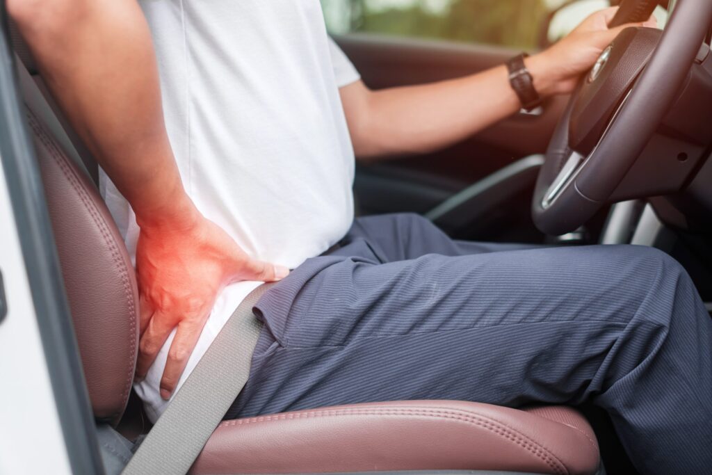 Man holding his back in pain while driving