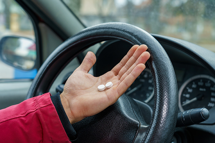 person holding pills while driving
